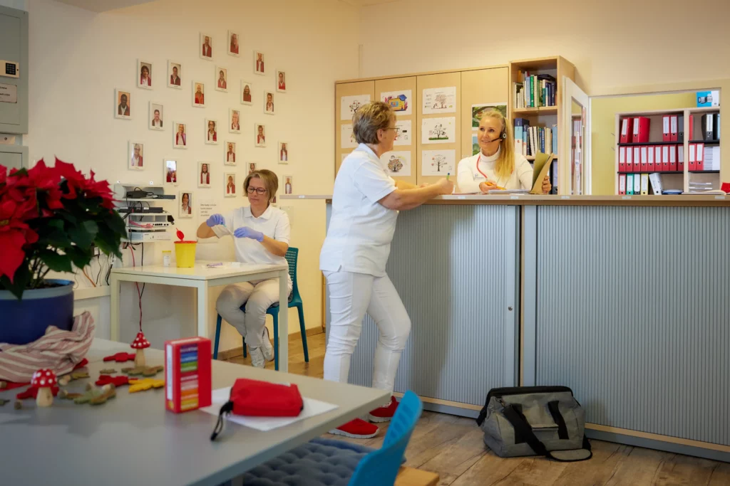 Mitarbeiterinnen sprechen an der Rezeption des Pflegedienstes